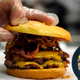 Hand placing top burger bun on finished smash burger